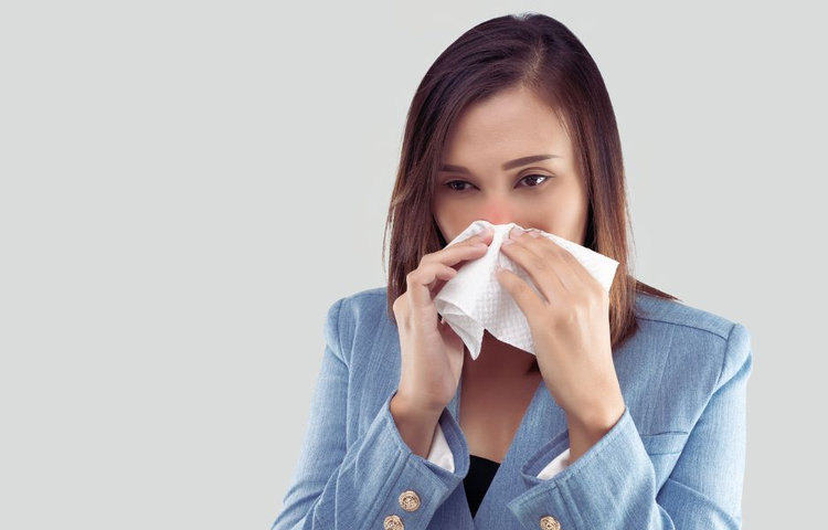 Žena s vreckovkou pri nose počas alergickej reakcie