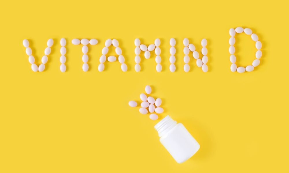  Tablety usporiadané do nápisu vitamín D vedľa otvorenej liekovky znázorňujú suplementáciu vitamínu D, jeho význam pri nedostatku slnka a podporu imunity počas zimných mesiacov.