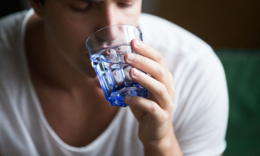  Muž pije vodu ako prevencia pred úpalom a dehydratáciou v letných horúčavách