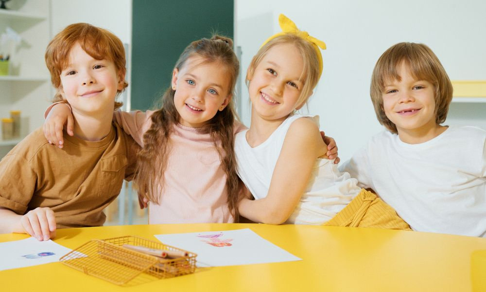  Usmiate deti s kresbami sedia spolu v triede, potreby do školy pre malého školáka